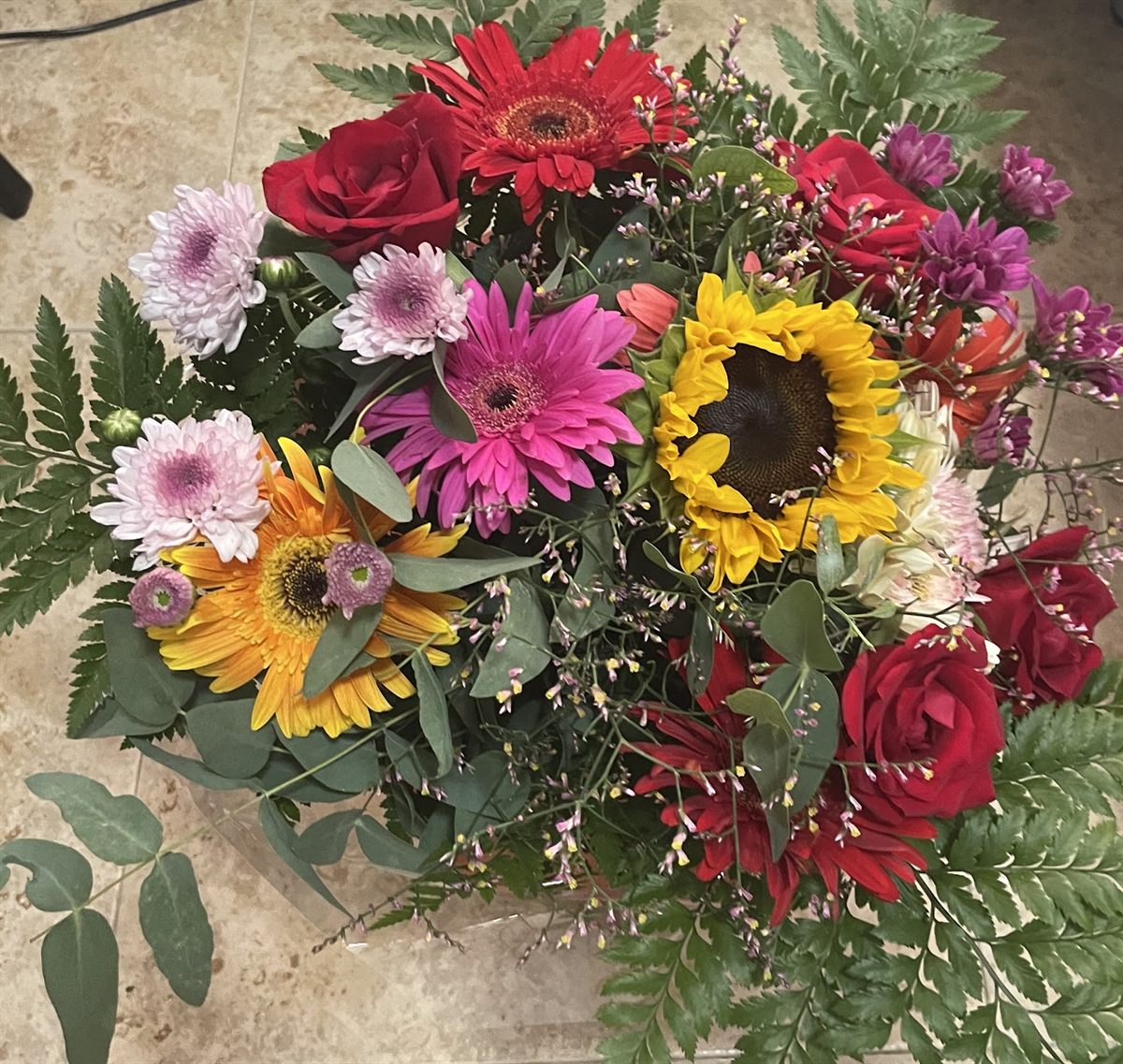 Ramo de temporada con girasoles, gerberas rosas y rosas rojas